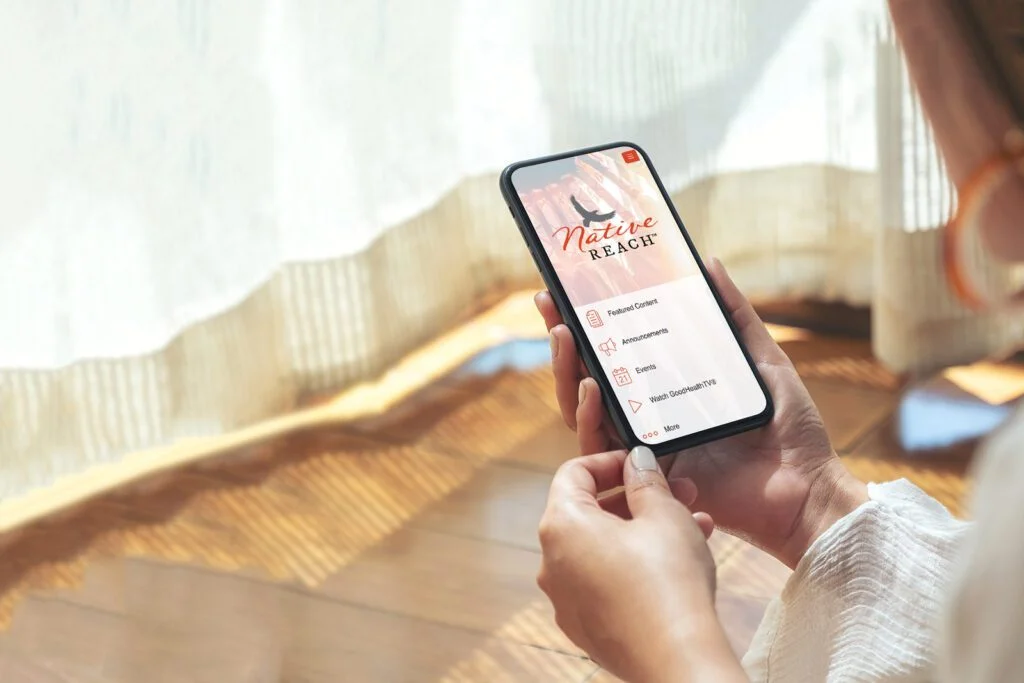 Mockup image of a woman holding and using black mobile phone. Native Reach.